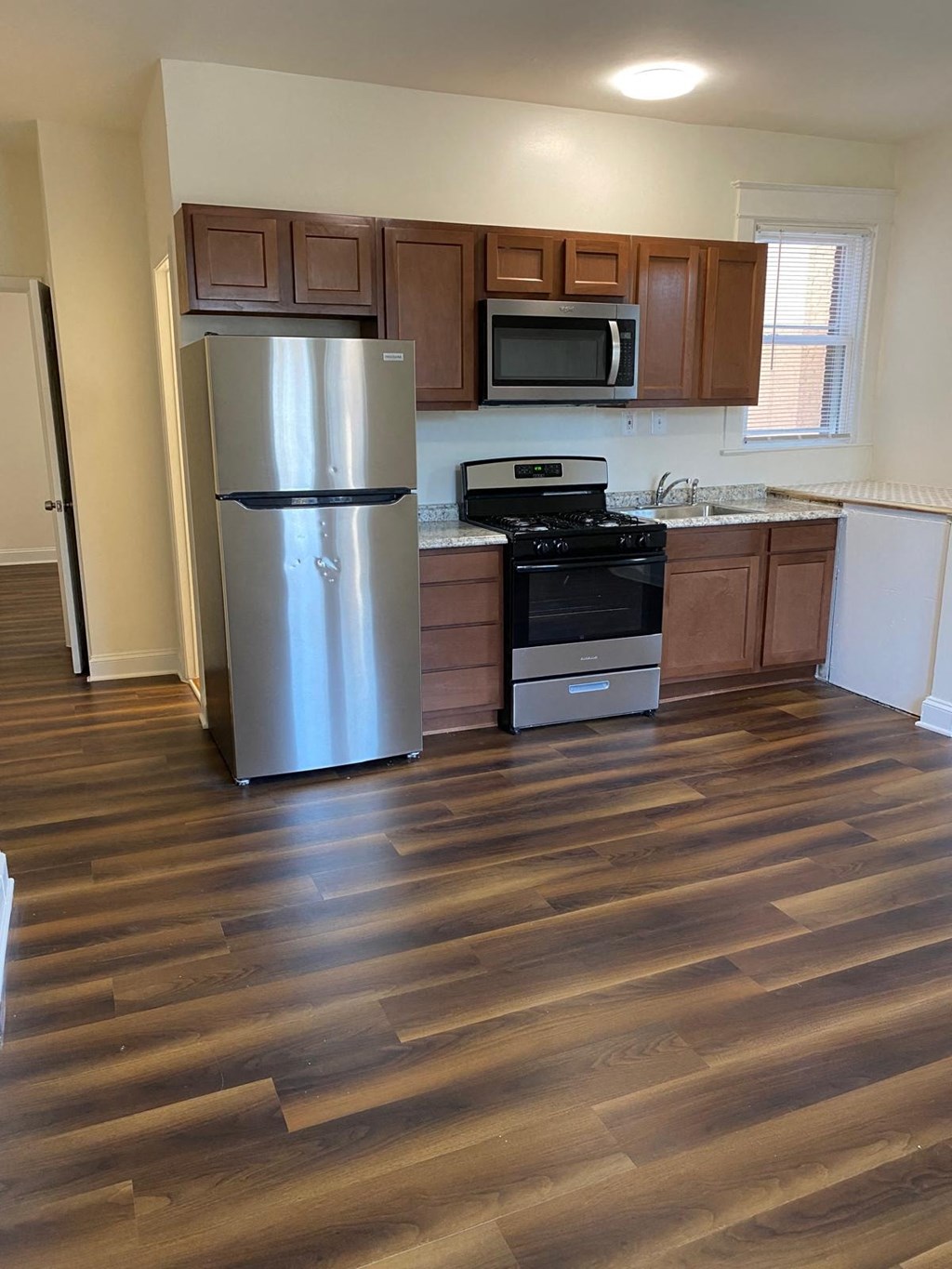 a kitchen with wooden floors and a stainless steel refrigerator