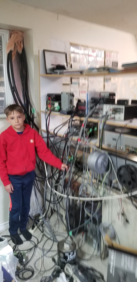 a young boy standing in a room with lots of wires and equipment