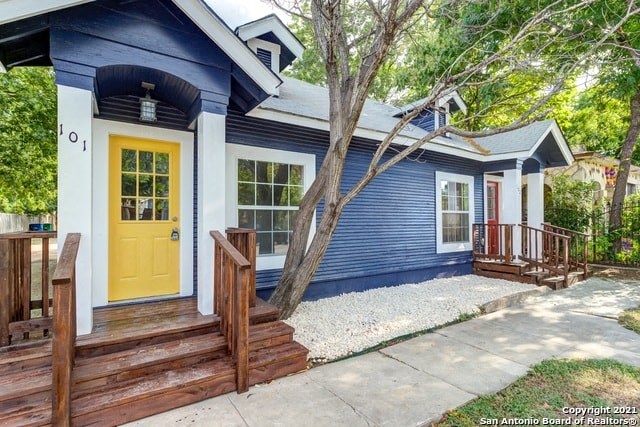 a blue house with a yellow door and a porch