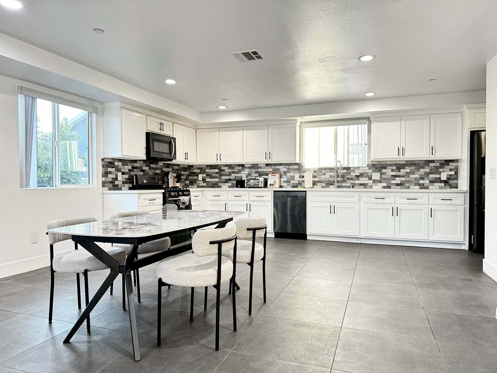 a kitchen with white cabinets and a table with chairs