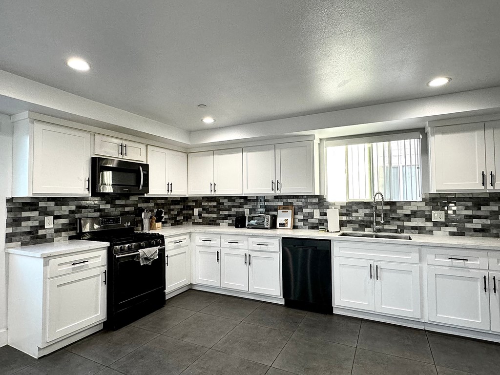 a kitchen with white cabinets and black appliances