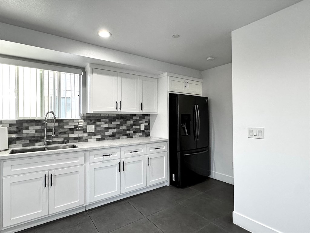 a kitchen with white cabinets and a black refrigerator