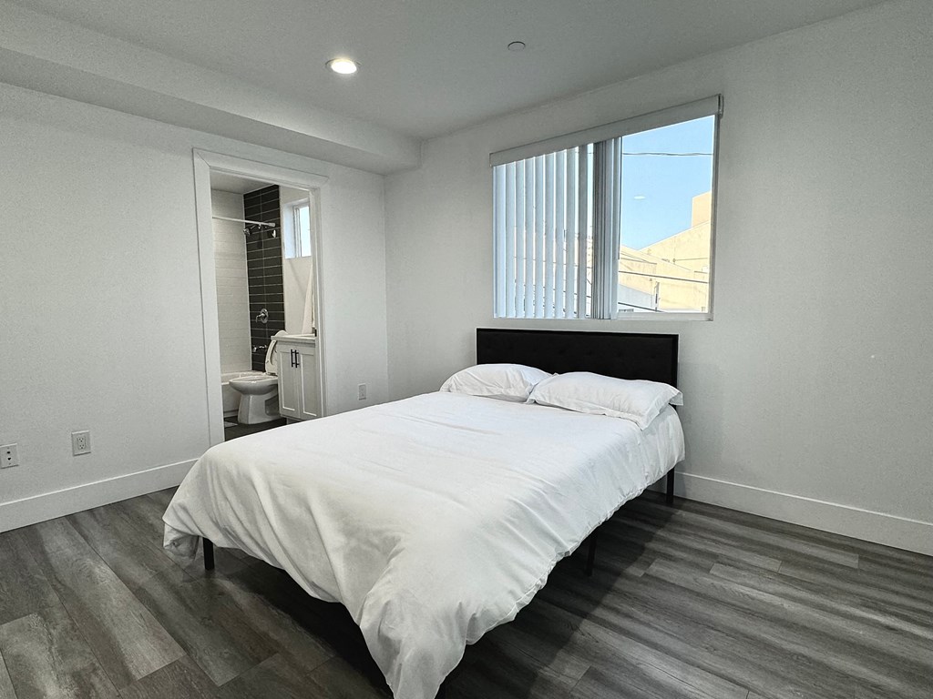 a bedroom with a bed and a toilet and a window