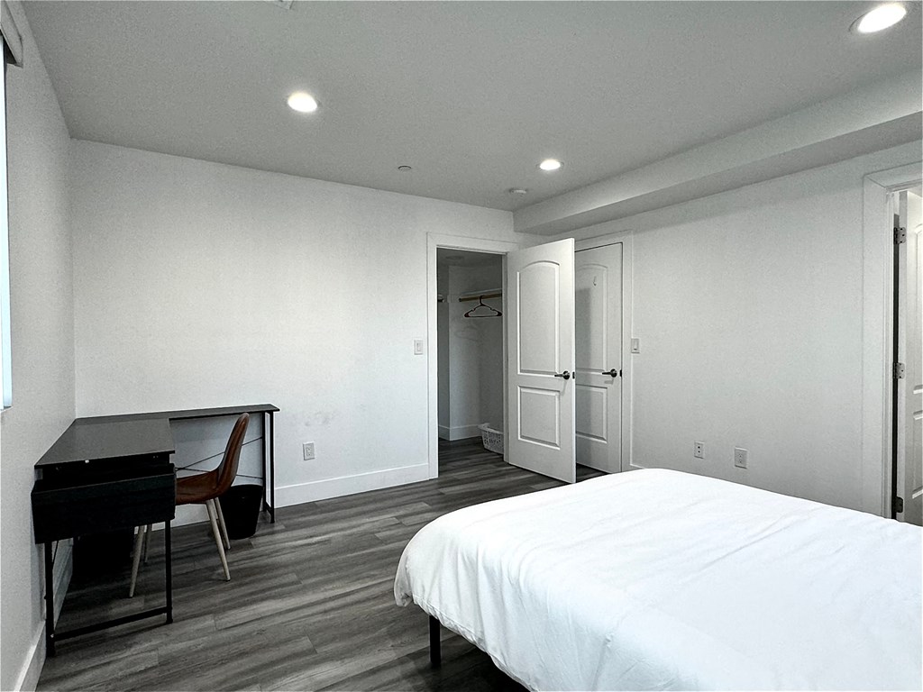 a white bedroom with a bed and a desk