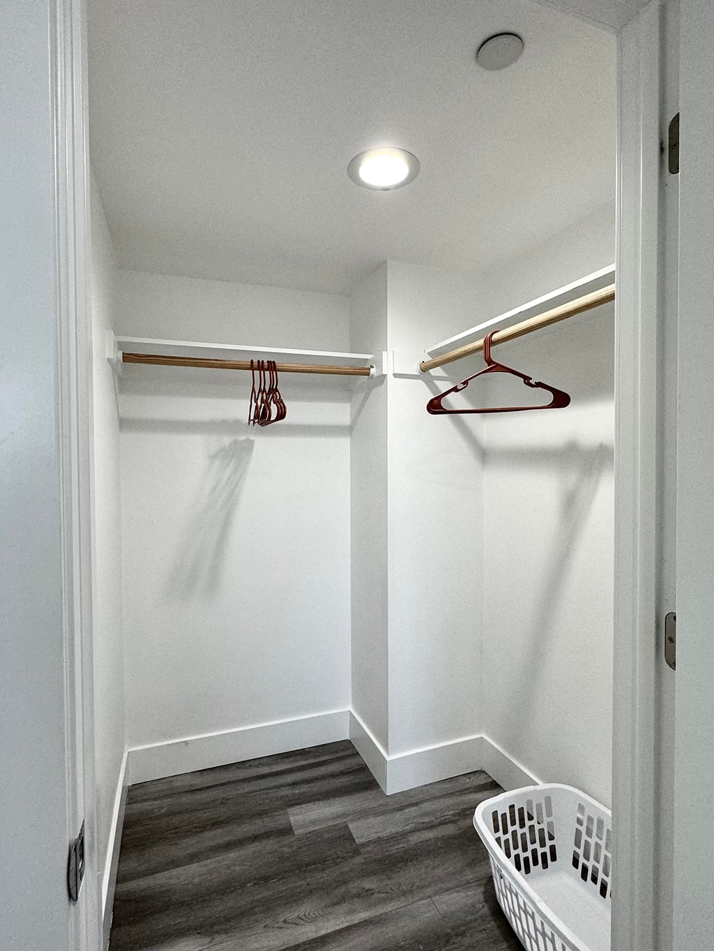 a walk in closet with a basket and a hanger on the wall