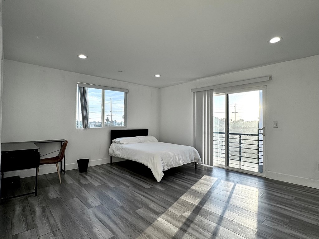a bedroom with a bed and a desk and a balcony