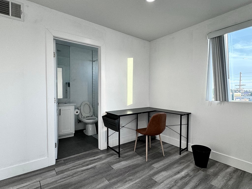 a small room with a desk and a bathroom with a toilet