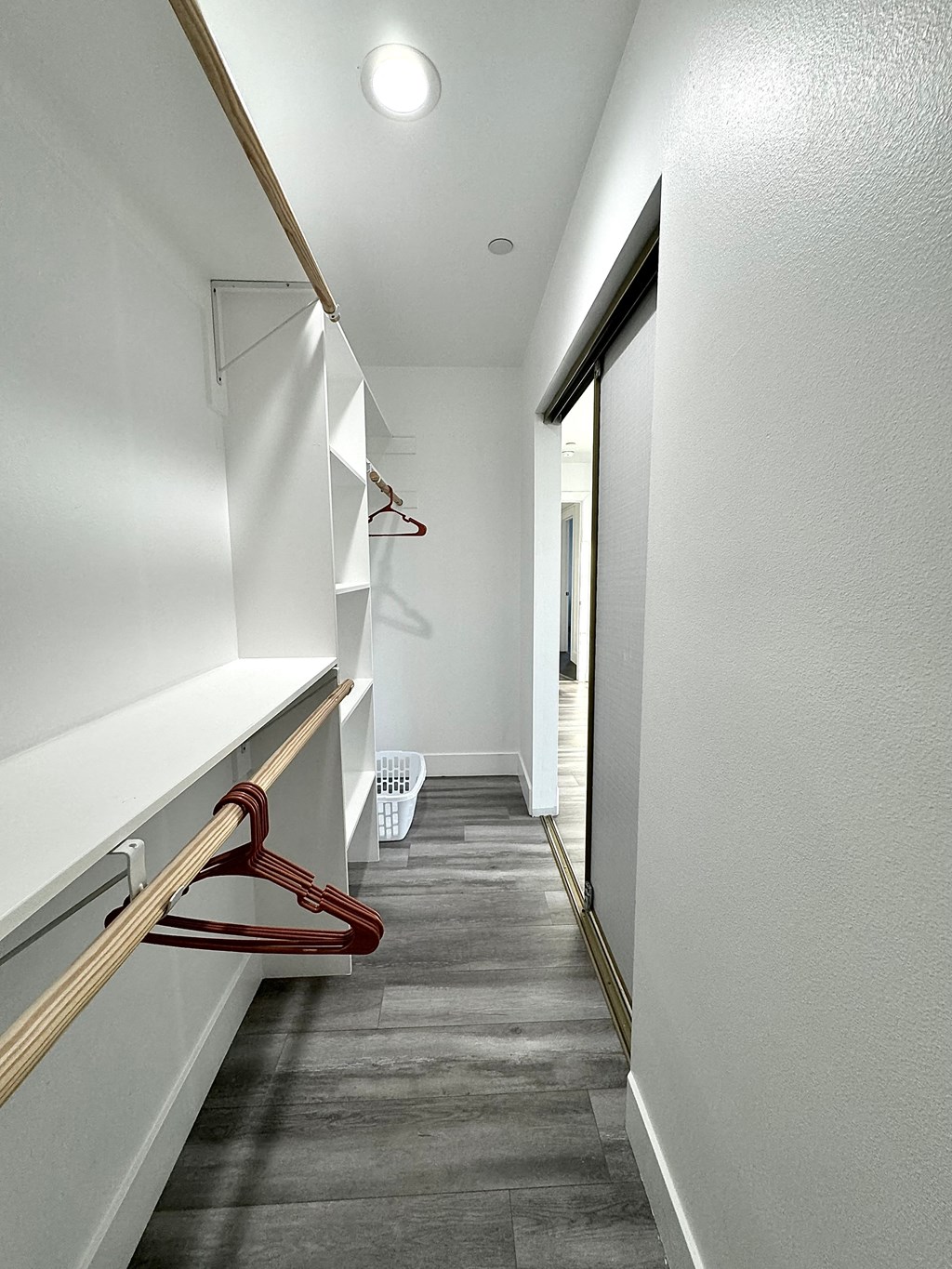 a long hallway with white walls and a door to a hallway with a hallway mirror