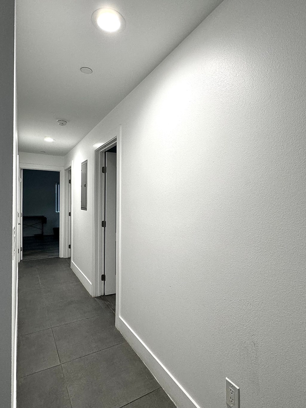 a hallway with a white wall and a door to a bedroom