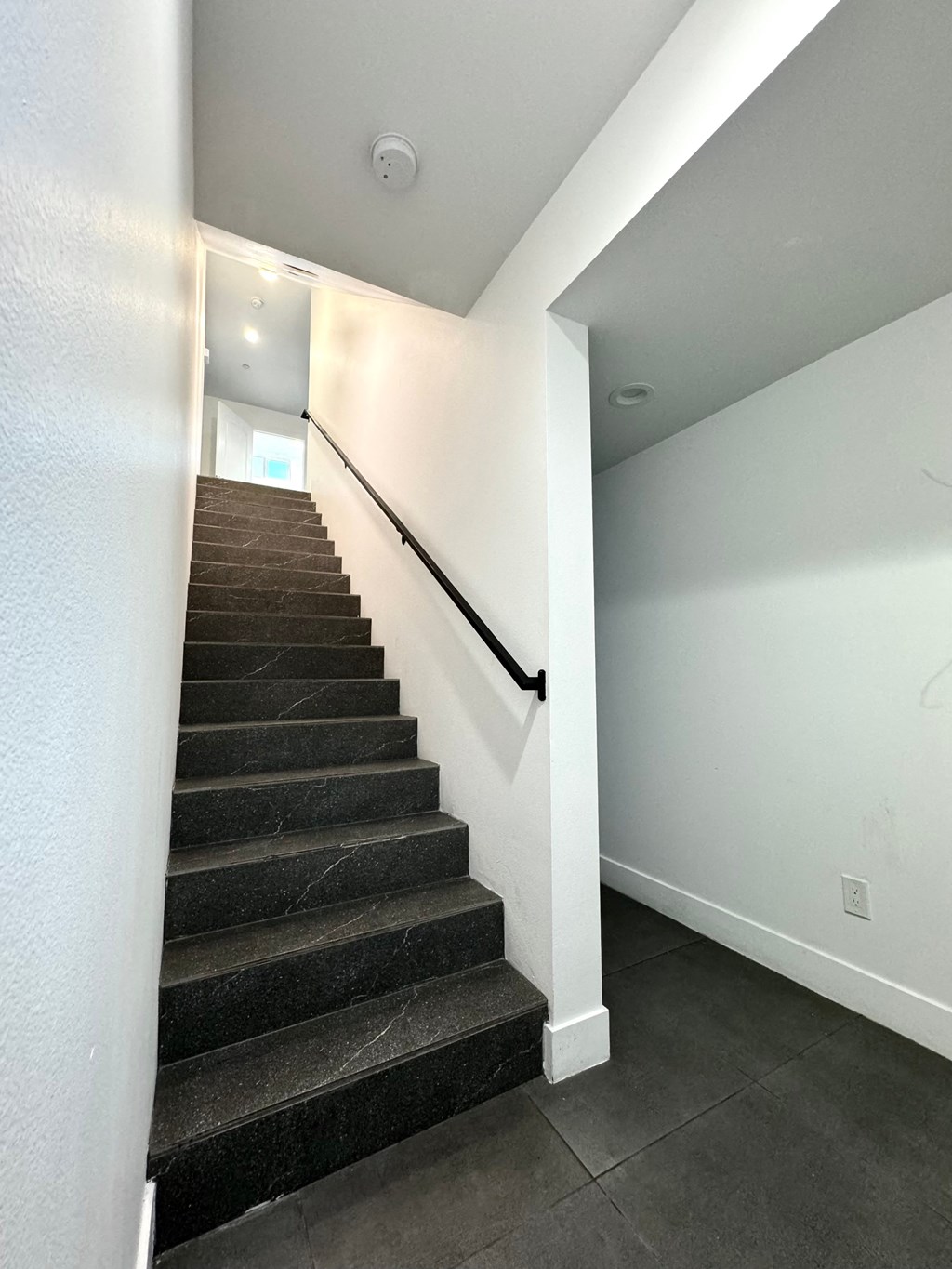 a staircase in a home with a black carpeted stairwell and white walls