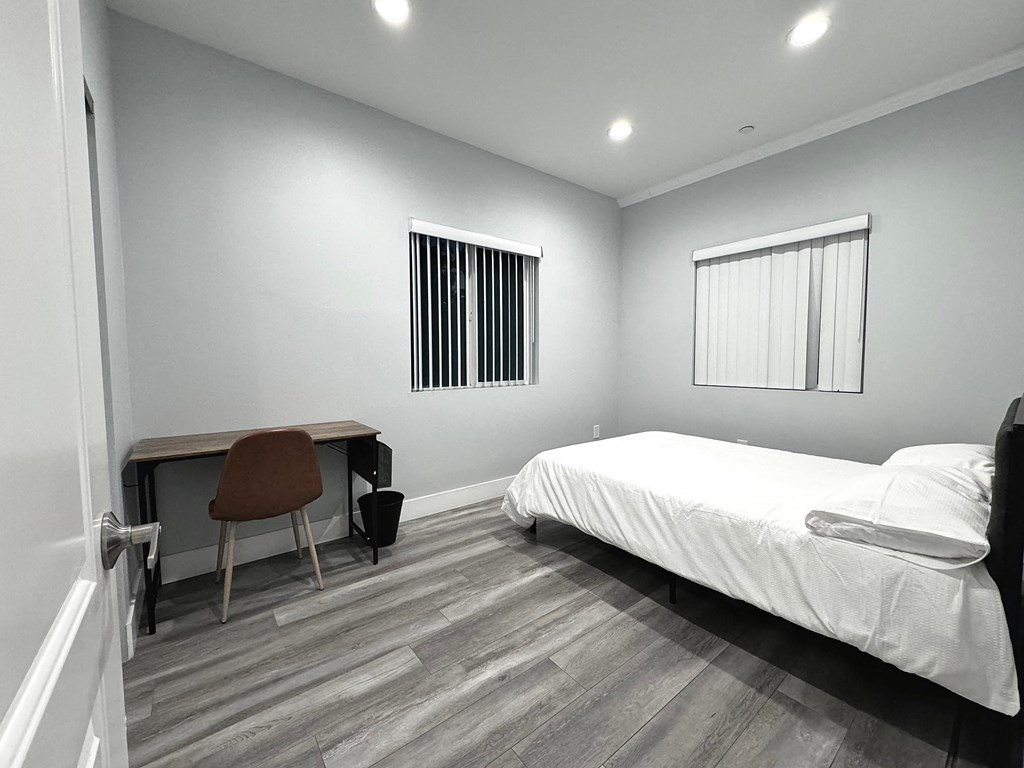 a bedroom with a bed and a desk and a window