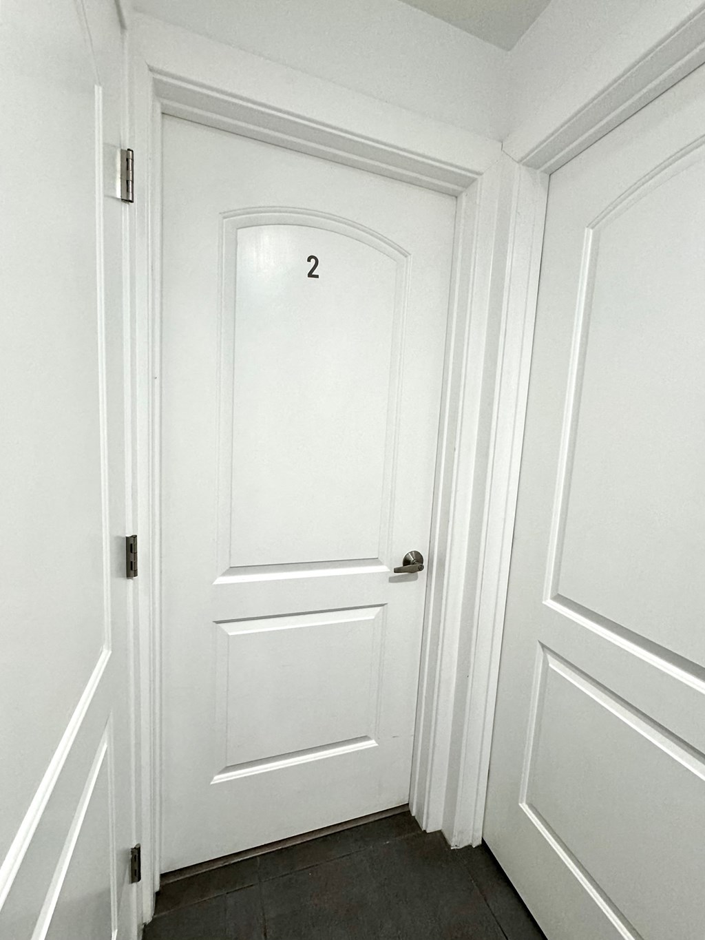 a white hallway with a white door with a number 2 on it