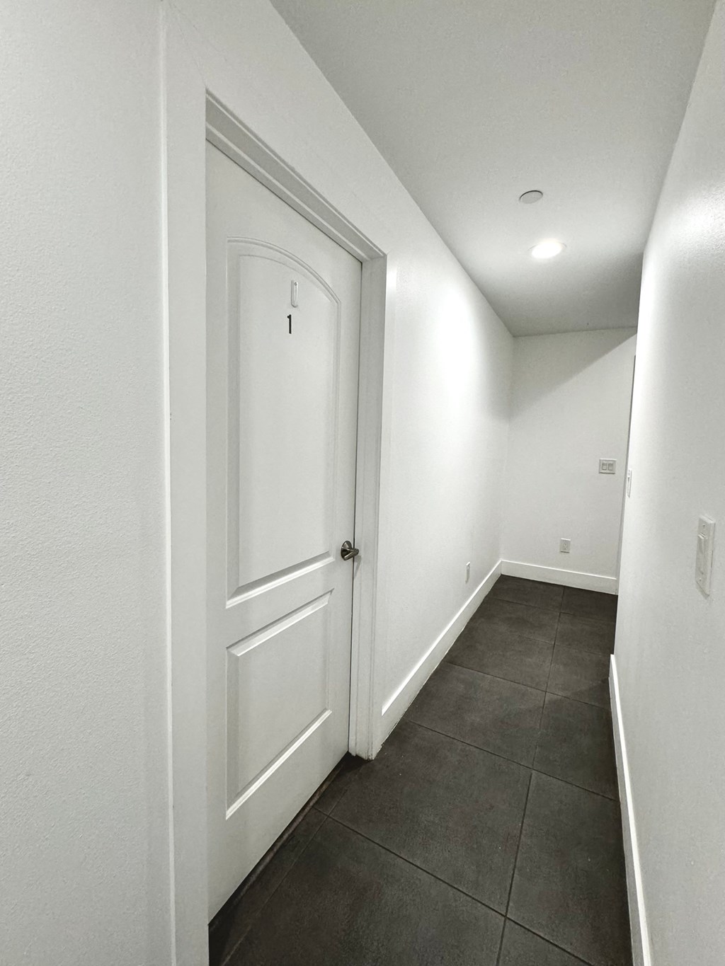a white hallway with a white door and a tiled floor