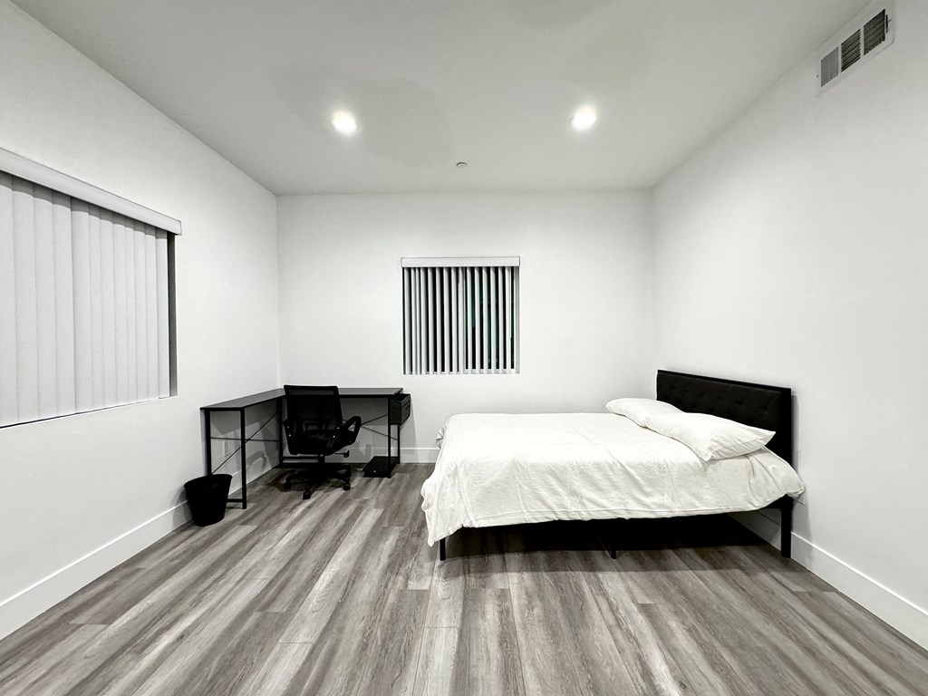 a bedroom with a bed and a chair and a window