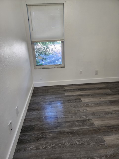 A room with a window and wooden flooring.