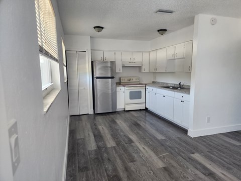 A kitchen with white cabinets and a grey floor.