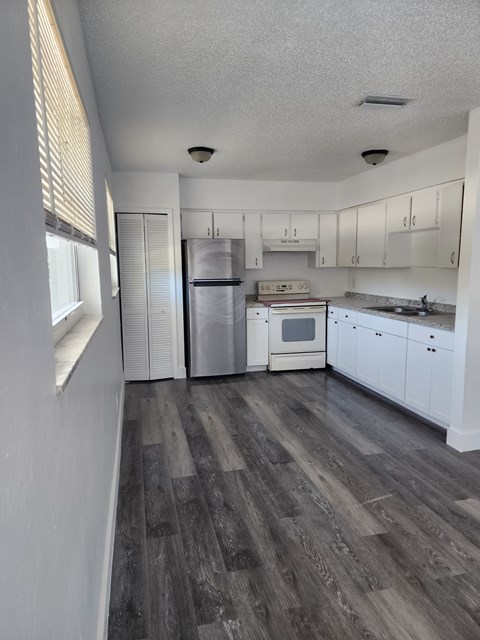 A kitchen with white cabinets and a wooden floor.