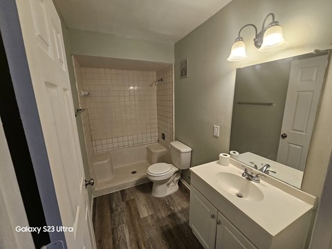 A bathroom with a white sink, toilet, and a bathtub with a shower head.