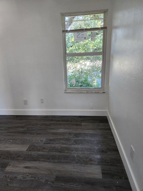 A room with a window and wooden flooring.