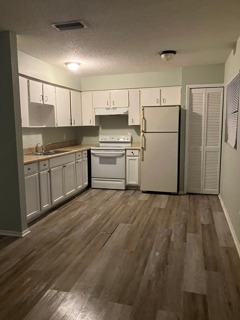 A kitchen with white cabinets and a white refrigerator.