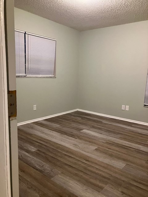 A room with wooden flooring and a window with blinds.