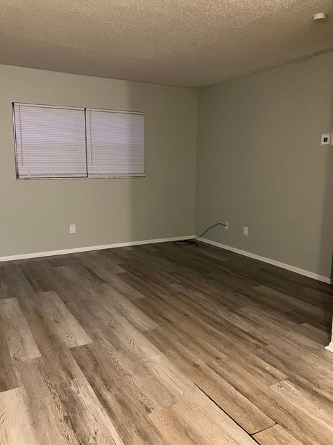 A room with wooden flooring and a window with blinds.