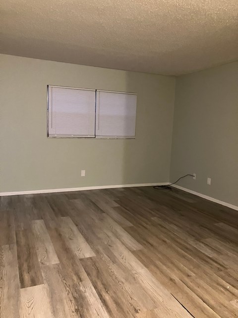 A room with wooden flooring and a window with blinds.