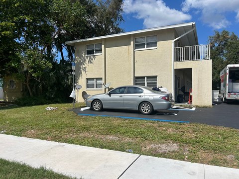 A silver car is parked in front of a two-story building.