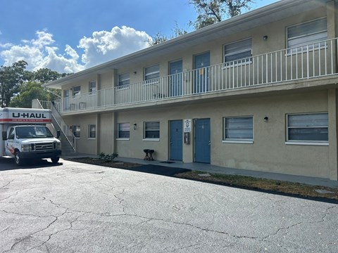 A U-Haul van is parked in front of a building with a blue door.