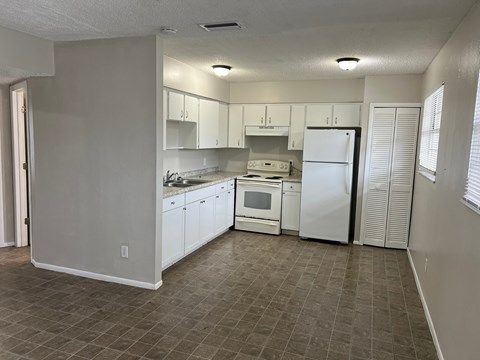 A kitchen with white cabinets and appliances.
