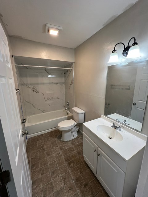 A bathroom with a toilet, sink, and tub.