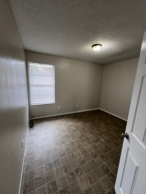 A room with a tiled floor and a window with blinds.