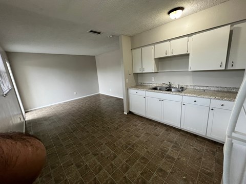 A kitchen with brown tiles and white cabinets.