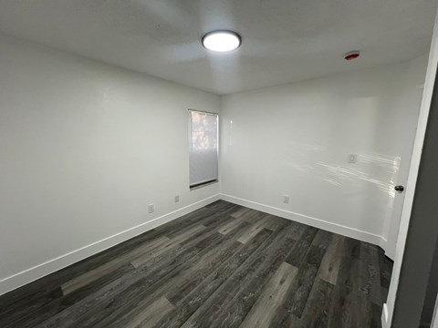 A room with wooden flooring and a window with blinds.