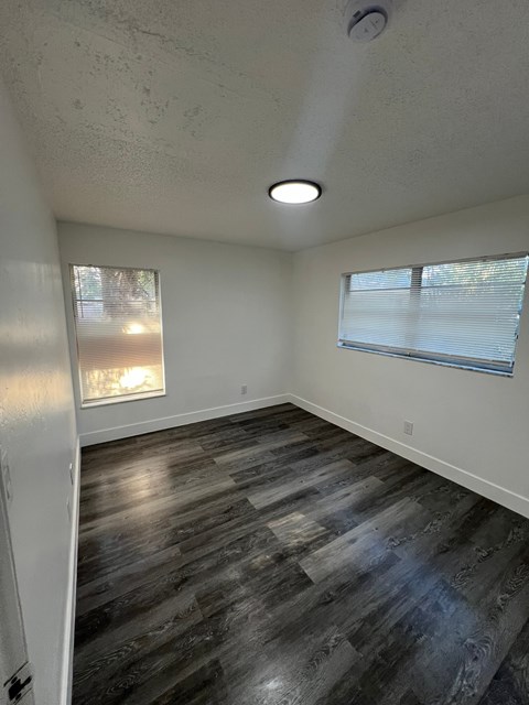 A room with a wooden floor and a window with blinds.
