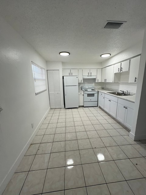 A kitchen with white appliances and cabinets.