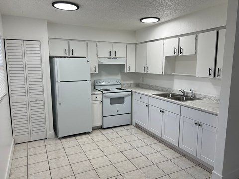 A kitchen with white appliances and cabinets.