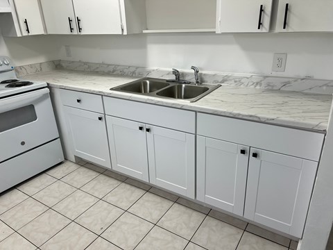 A kitchen with white cabinets and a marble countertop.