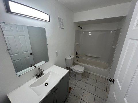 A white bathroom with a sink, toilet and bathtub.