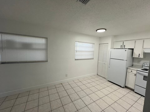 A kitchen with white appliances and a tiled floor.