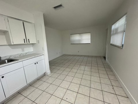 A kitchen with white cabinets and a tiled floor.