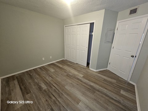 A room with a wooden floor and two white doors.
