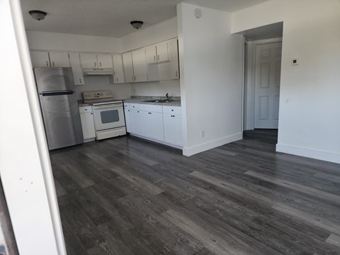 A kitchen with white cabinets and a wooden floor.