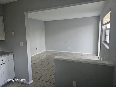 A kitchen with white cabinets and a tiled floor.