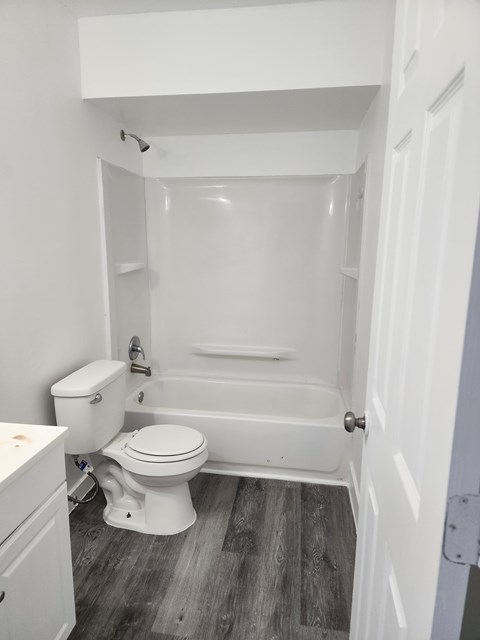 A white toilet and bathtub in a small bathroom.