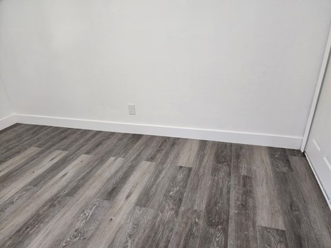 A room with a wooden floor and a white wall.