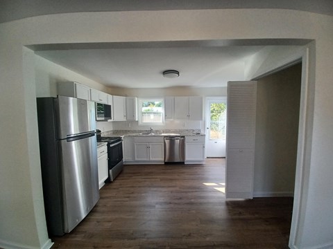 A kitchen with white cabinets and a stainless steel refrigerator.