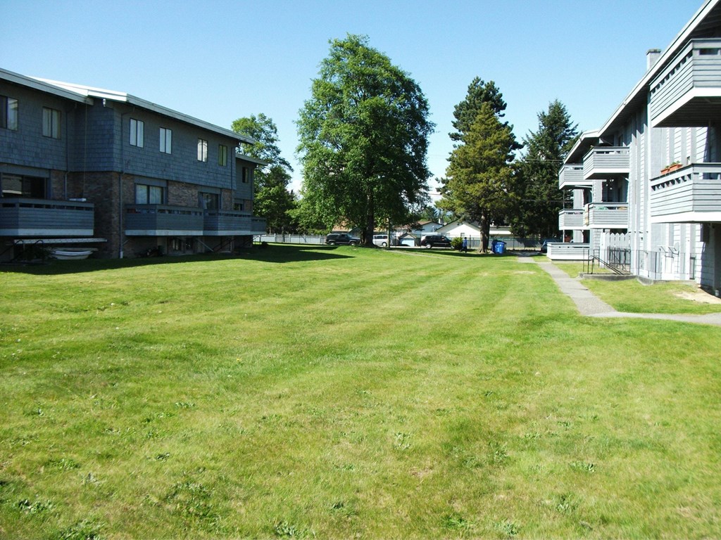 A grassy field in front of apartment buildings.
