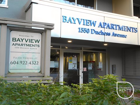 The front of Bayview Apartments with a sign welcoming people to the building.