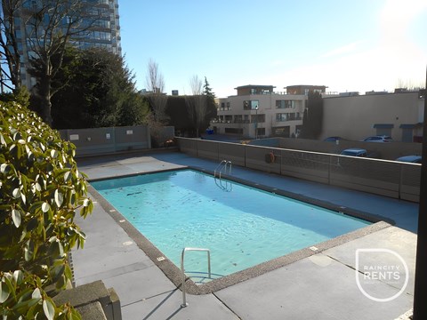 A swimming pool surrounded by a concrete wall and a metal ladder.
